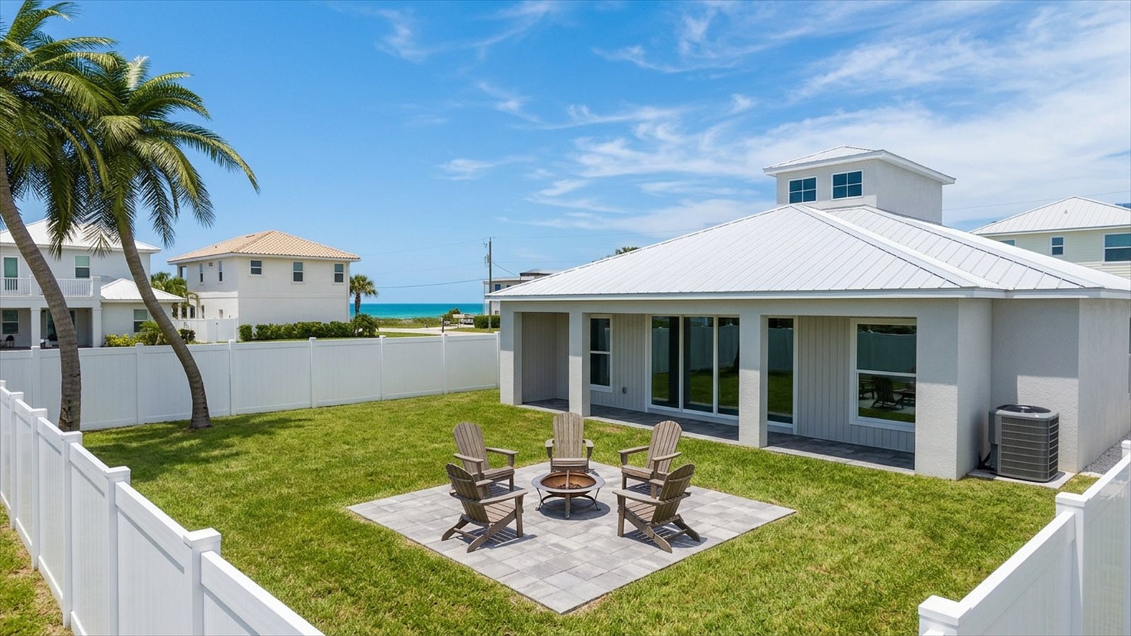 Backyard before pool installation — coconut palms, vinyl fence, simple paver patio with fire pit